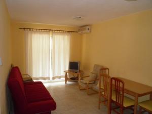 ein Wohnzimmer mit einem roten Sofa und einem Tisch mit Stühlen in der Unterkunft Amber House Apartments Supetar-Brac in Supetar