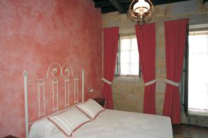 a bedroom with a white bed with red walls and windows at Pazo Da Escola in A Moreira