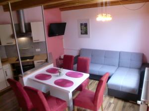 ein Wohnzimmer mit einem weißen Tisch und roten Stühlen in der Unterkunft Garten- & Loggia-Appartement HERRENHAUS in Dellach im Drautal