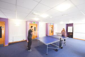 a man standing in a room with a ping pong table at Bushmills Youth Hostel in Bushmills