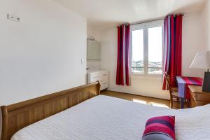ビアリッツにあるApartment Welkeys Biarritz Pringleのベッドルーム1室(ベッド1台付)、赤いカーテン付きの窓が備わります。