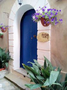 une porte bleue avec un panneau et quelques fleurs violettes dans l'établissement afra Bed & Breakfast, à Castellabate