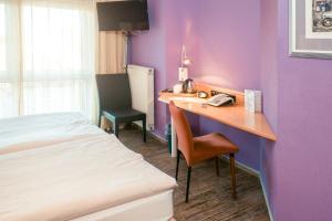 a hotel room with a bed and a desk with a phone at Ambiente Langenhagen Hannover by Tulip Inn in Hannover