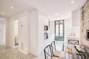 cocina y sala de estar con paredes blancas, mesa y sillas en Flateli Rambla 5 2-1, en Girona