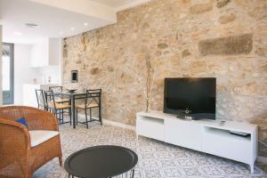 sala de estar con TV en una pared de piedra en Flateli Rambla 5 2-1, en Girona