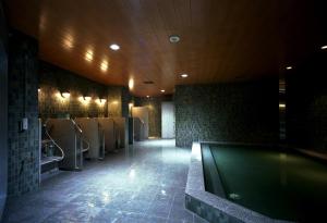 - une salle de bains avec une piscine et une rangée d'urinoirs dans l'établissement Higashi Hiroshima Green Hotel Morris, à Higashihiroshima