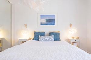 a bedroom with a white bed with blue pillows at Pina I by An Island Apart in Funchal