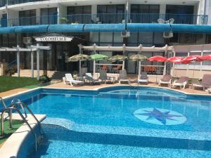 a swimming pool with chairs and umbrellas next to a building at Colosseum 2 Aparthotel in Sunny Beach