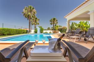 a table with wine glasses next to a swimming pool at Villa Amarela in Alvor