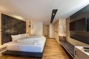 a bedroom with a large white bed and a flat screen tv at Hotel des Alpes in Samnaun