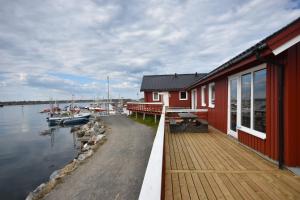 a red house with a deck next to the water at Lankanholmen in Andenes