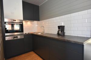 a kitchen with black cabinets and a sink and a stove at Lankanholmen in Andenes