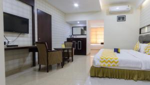 a hotel room with a bed and a desk and a television at Hotel Southern Residency in Kelambākkam