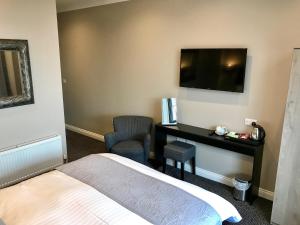 a hotel room with a bed and a desk and a television at The Raven Hotel in Corby