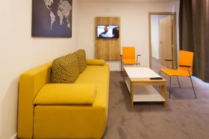 a living room with a yellow couch and orange chairs at Chess Apartments in Belgrade