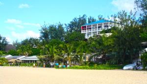 a building on the side of a beach with trees at Casa Do Mar Guest House in Praia do Tofo