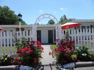 a white fence with flowers in front of a house at Claddagh Motel & Suites in Rockport