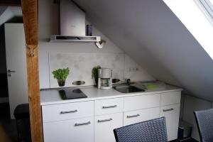 una cocina con armarios blancos y fregadero en 2raum Lüneburg, en Lüneburg