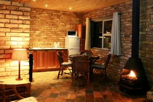 une cuisine avec une cheminée, une table et des chaises dans l'établissement Thirsty Falls Guest Farm, à Maanhaarrand
