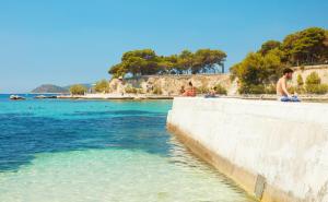 a group of people sitting on a wall near the water at Studio Apartman Kaćunić in Split