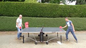 two men playing ping pong on a ping pong table at Camping les Tournesols in Sillé-le-Guillaume