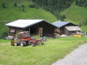 einem Traktor, der auf einem Feld neben einem Gebäude geparkt ist in der Unterkunft Pension Hedegghof in Großarl