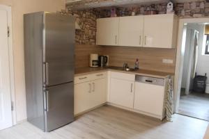 a kitchen with a stainless steel refrigerator and white cabinets at Ferienhaus Erholungsparadies im schönen Franken in Obertheres