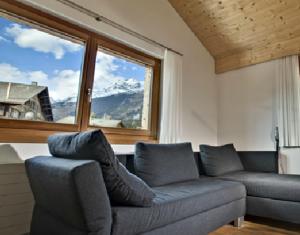 ein Wohnzimmer mit einem Sofa und einem großen Fenster in der Unterkunft Apartment Alpina in Brigels