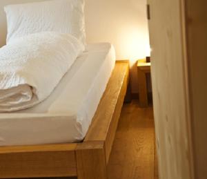 ein Bett mit weißer Bettwäsche und Kissen darauf in der Unterkunft Apartment Alpina in Brigels
