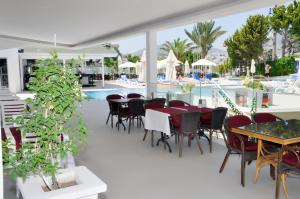 a patio with tables and chairs and a pool at Siesta Beach Apartment in Gümbet