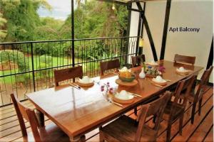 einen hölzernen Esstisch mit Stühlen und einen Balkon in der Unterkunft Kiloran House in Nairobi