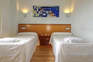 Habitación con 2 camas y una pintura en la pared. en Hostal Restaurante Taracena en Yunquera de Henares