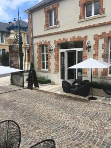 un patio avec des chaises et des parasols en face d'un bâtiment dans l'établissement Champagne André Bergère, à Épernay