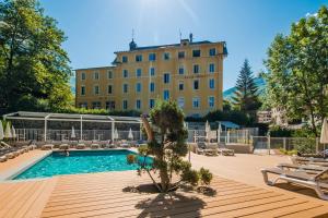 una piscina con sillas y un edificio de fondo en Savoy Hôtel en Brides-les-Bains
