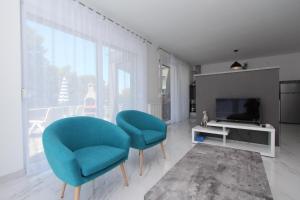 a living room with two blue chairs and a television at Apartment Karlo 2 in Rovinj