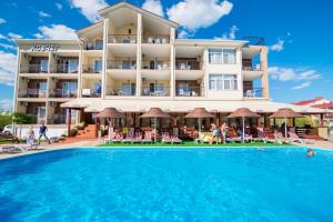 a hotel with a swimming pool in front of a building at Kovcheg Hotel in Zatoka