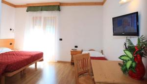 a bedroom with two beds and a tv on the wall at Hotel K2 in Andalo