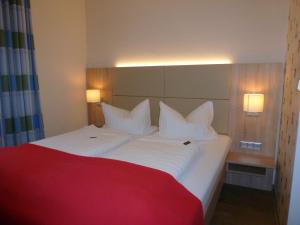 1 dormitorio con cama blanca y manta roja en Hotel das Möwenstübchen en Wremen