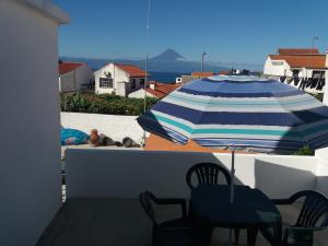 a patio with a blue and white umbrella and chairs at AzoresDream in Velas