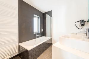 La salle de bains est pourvue d'une baignoire blanche et d'un lavabo. dans l'établissement Smartflats - Toison d'Or, à Bruxelles