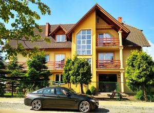 a car parked in front of a yellow house at Słoneczne Uroczysko in Międzywodzie