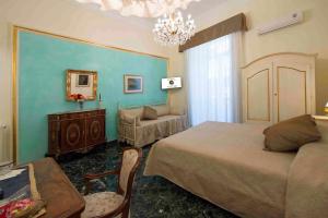 una camera con due letti, un divano e un lampadario a braccio di B&B Residenza Via Dei Mille a Napoli