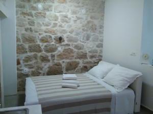 a bed in a room with a stone wall at Apartment Vidačak in Tisno