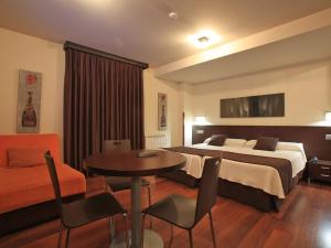 Habitación de hotel con cama, mesa y sillas en Apartamentos Rurales L'Arquera en Llanes