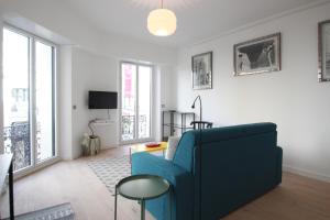 uma sala de estar com um sofá azul e algumas janelas em Palais Foch em Cannes