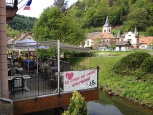 un restaurant avec un panneau sur un pont sur une rivière dans l'établissement Hôtel Des Vosges, à Lutzelbourg