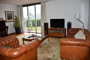 a living room with two leather couches and a television at Caloura Camellia House in Caloura