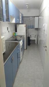 cocina con armarios azules, fregadero y fogones en Departamento Víctoria en Mar del Plata