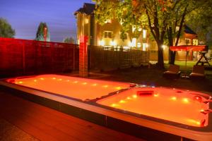 a hot tub with lights in a backyard at night at Hotel Lukács Superior in Kazincbarcika