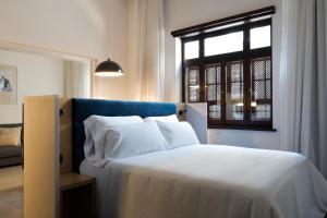 Schlafzimmer mit einem Bett mit weißer Bettwäsche und einem Fenster in der Unterkunft Suites 1478 in Las Palmas de Gran Canaria